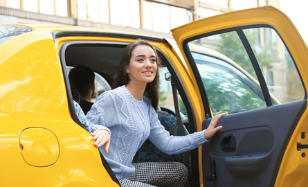 Young woman getting out of taxi