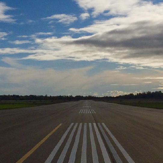 Bare runway with white lines down the middle and open blue sky