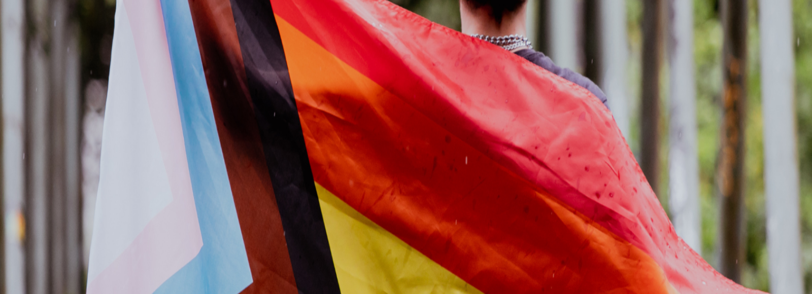 Person wrapped in the progressive Pride flag