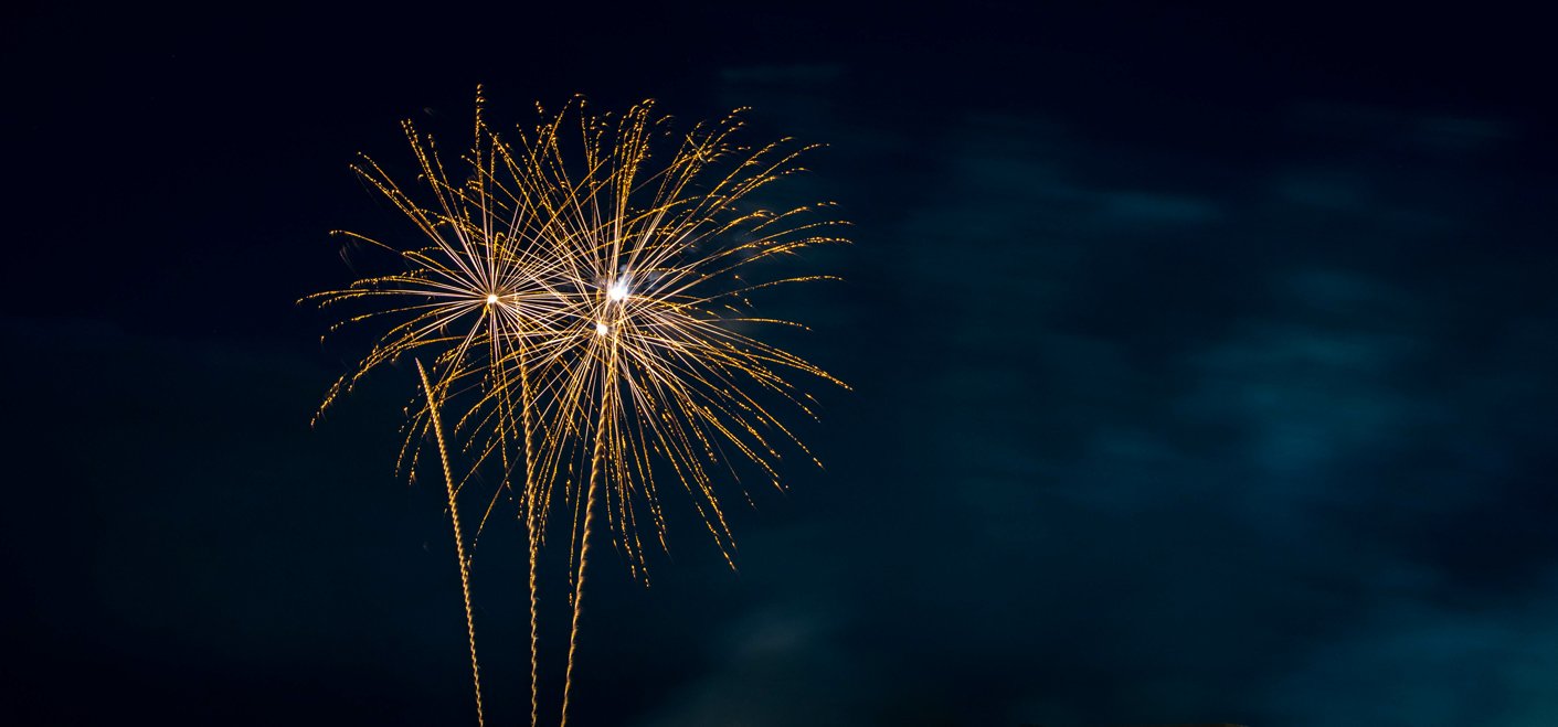 Gold fireworks exploding in a dark blue and black sky