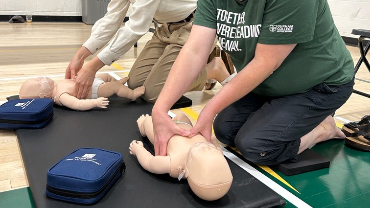 Two event participants kneel on a mat as they practice infant CPR.