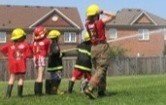 Kids in firefighter gear with a fire hose