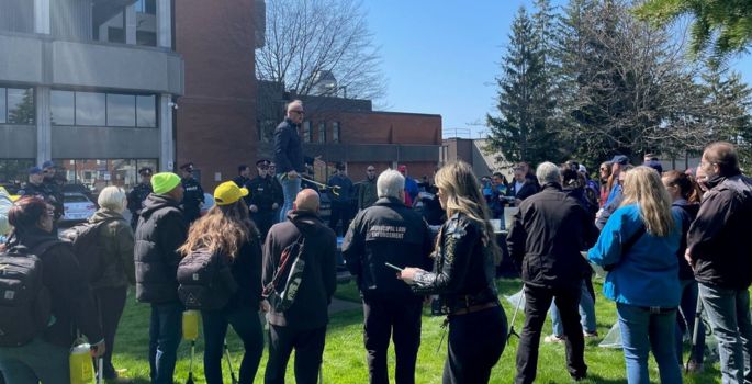 Group of people surround Oshawa Mayor Carter as they prepare for a community clean up.