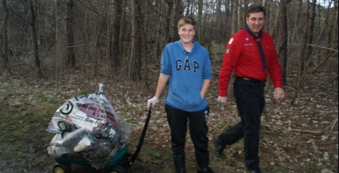 two people with a wheel barrow full of garbage