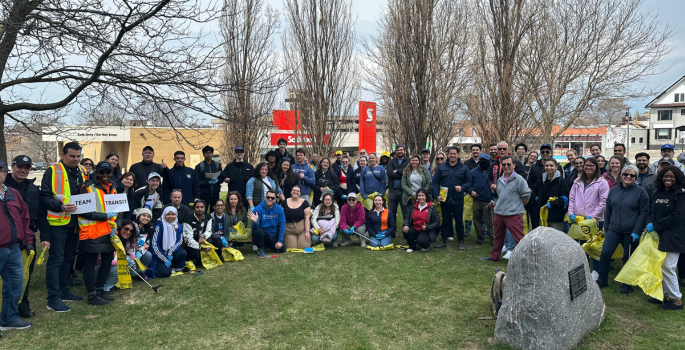 Group of people surround Oshawa Mayor Carter as they prepare for a community clean up.