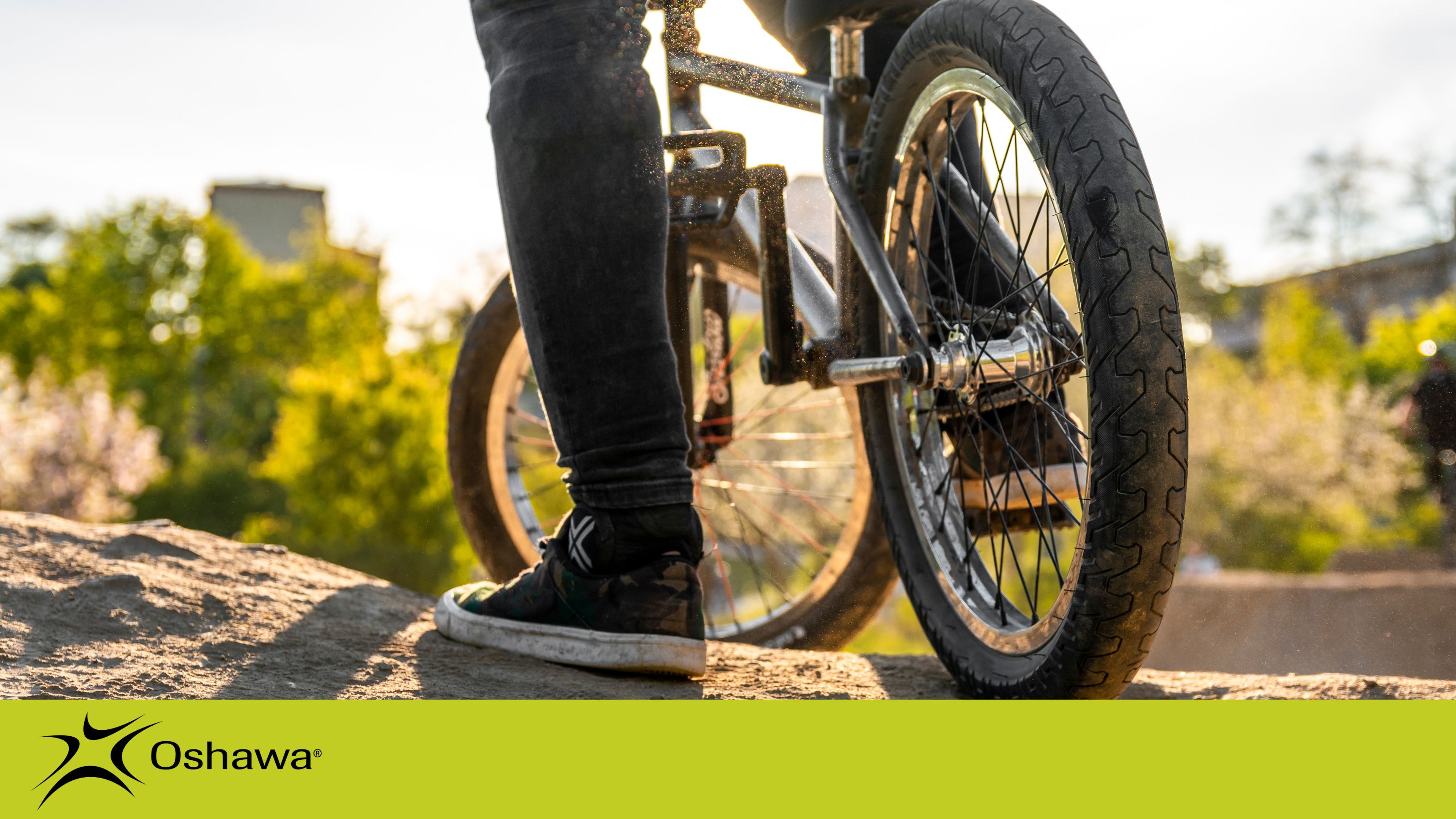 A rider's feet on the pedals of a BMX bike. The City's logo appears in black on the bottom left.