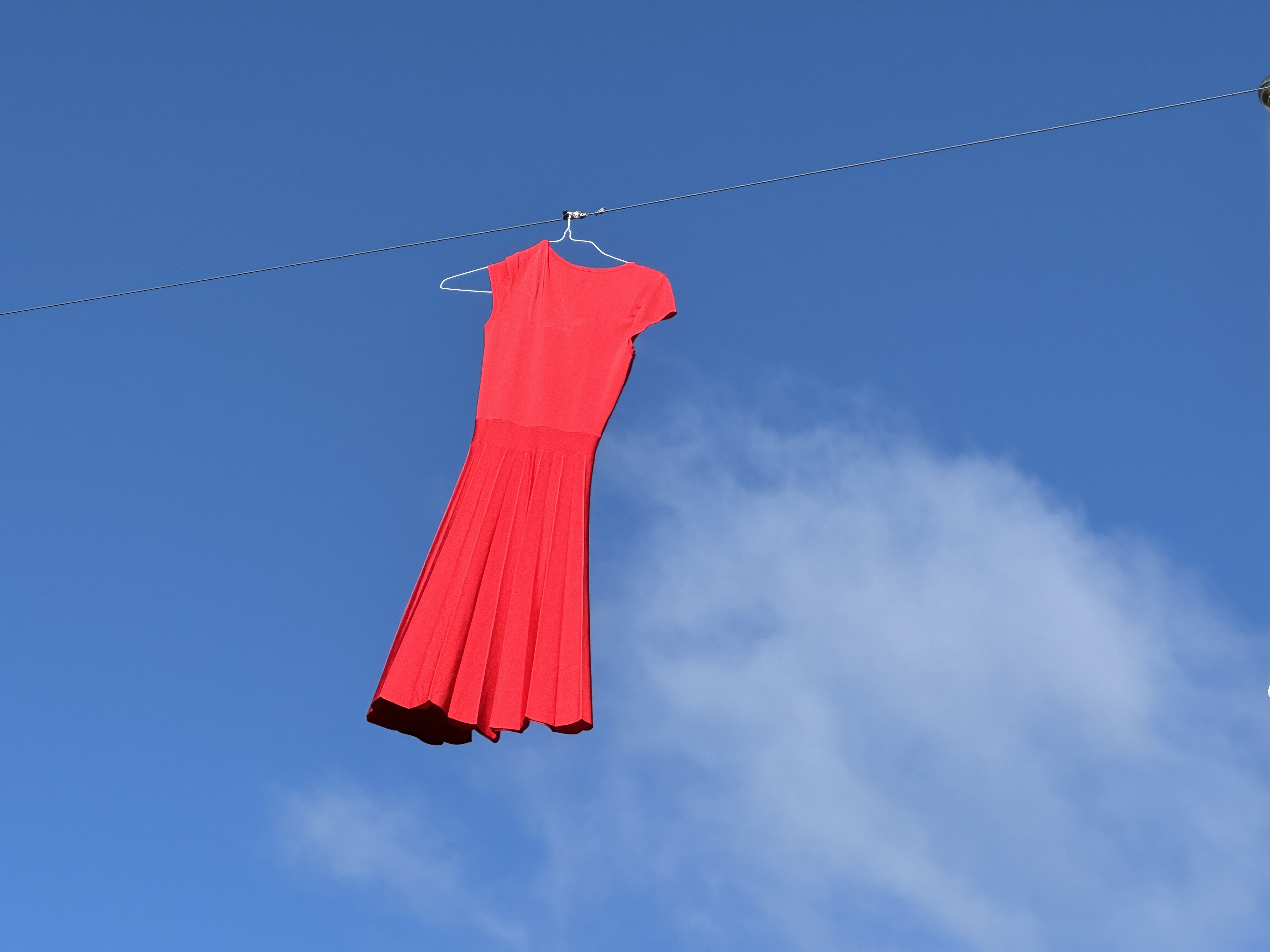 Red Dress blowing in the wind with a blue sly behind.