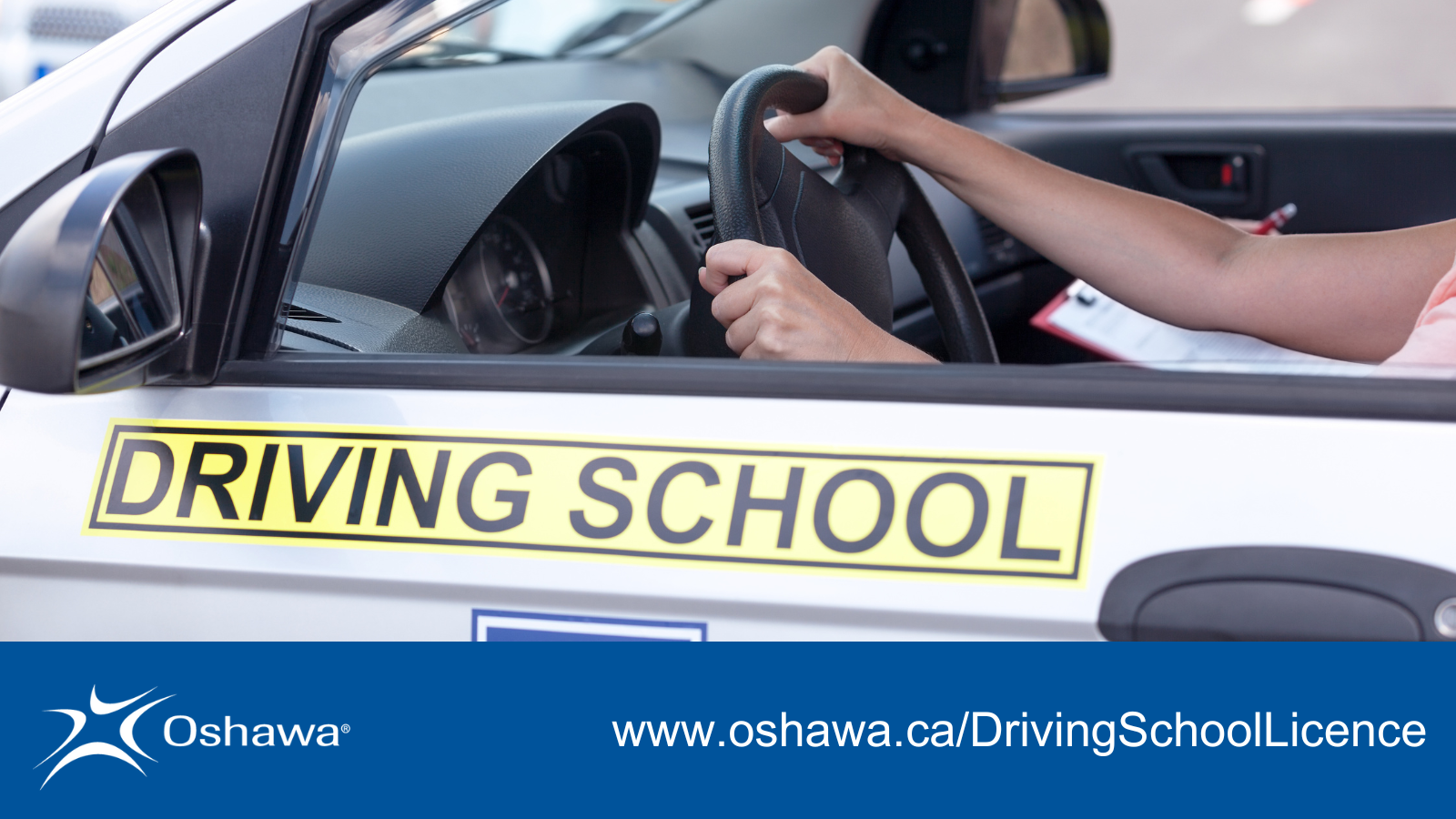 Person sitting in a car with two hands on the wheel. A sticker on the side of the car reads "Driving School"