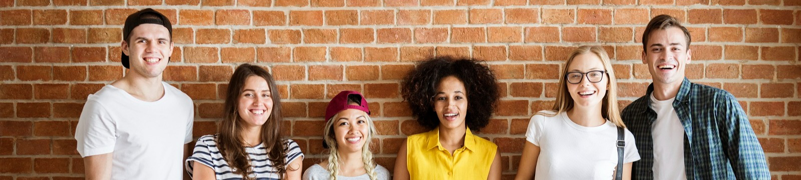 Five youth standing against a brick wall