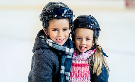 Boy and girl wearing hockey helmets