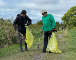 two people outdoors picking up garbage