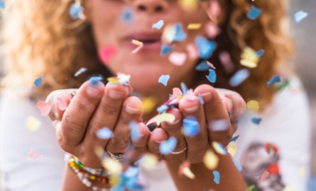 woman blowing confetti from their hands