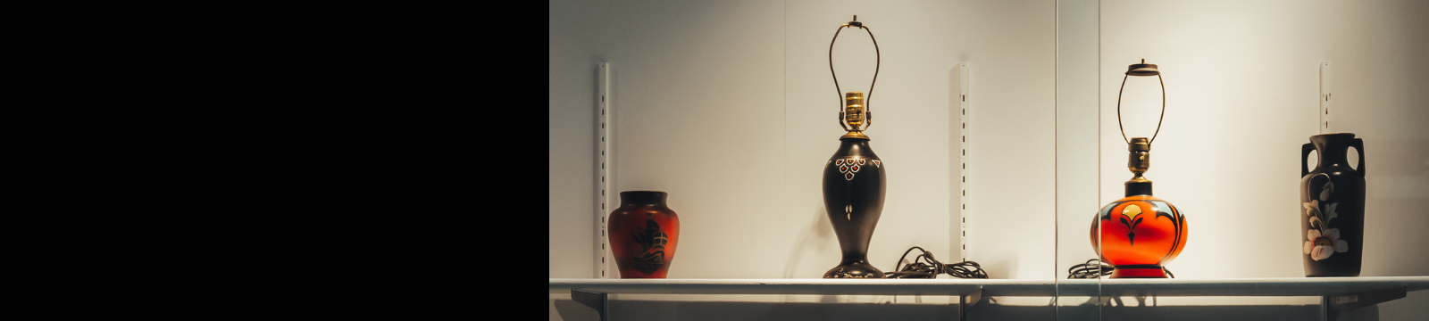 Items manufactured by Smith Potteries. From left to right: a red and black vase, a black lamp base, a red lamp base and a black vase with pink flowers.