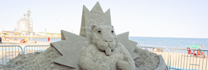 Sand sculpture of a beaver in front of a maple leaf