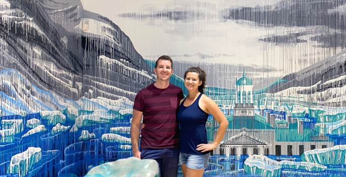 Amy Shackleton and Julian Brown standing in front of a water theme drip-paint mural with an augmented reality component