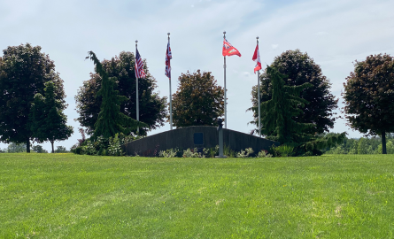 Camp X Monument surrounded by flags and park land/grass.