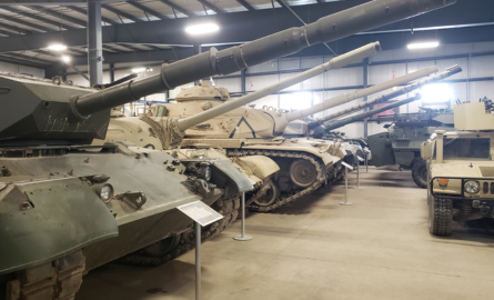 Military armoured tanks stored in rows, indoors.