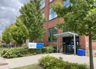 trees and shrubs in front of a red brick building