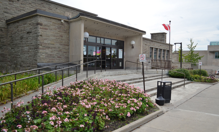 Exterior side image of main entrance of City library, showcasing gardens and main entrance doors.