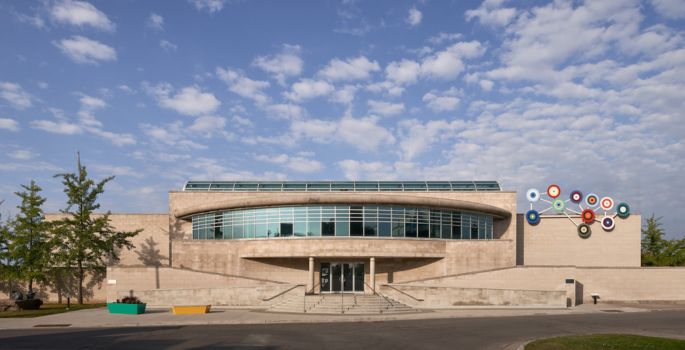 Exterior of Gallery, main stair case leading to front door and blue sky above building entrance with abstract art sculpture