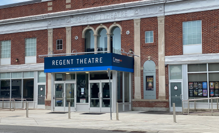 Exterior of historic building, main entrance with oversize sign indicating The Regent Theatre overhead.