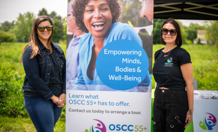 Two Staff on either end smiling with OSCC55+ Banner in Centre with image of female senior.