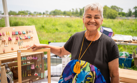 Indigenous Artist standing with her vendor materials of jewellery display.