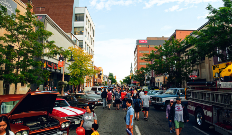 classic cars displayed downtown with people walking past them