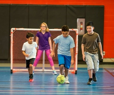 Four kids playing soccer in a gymnasium