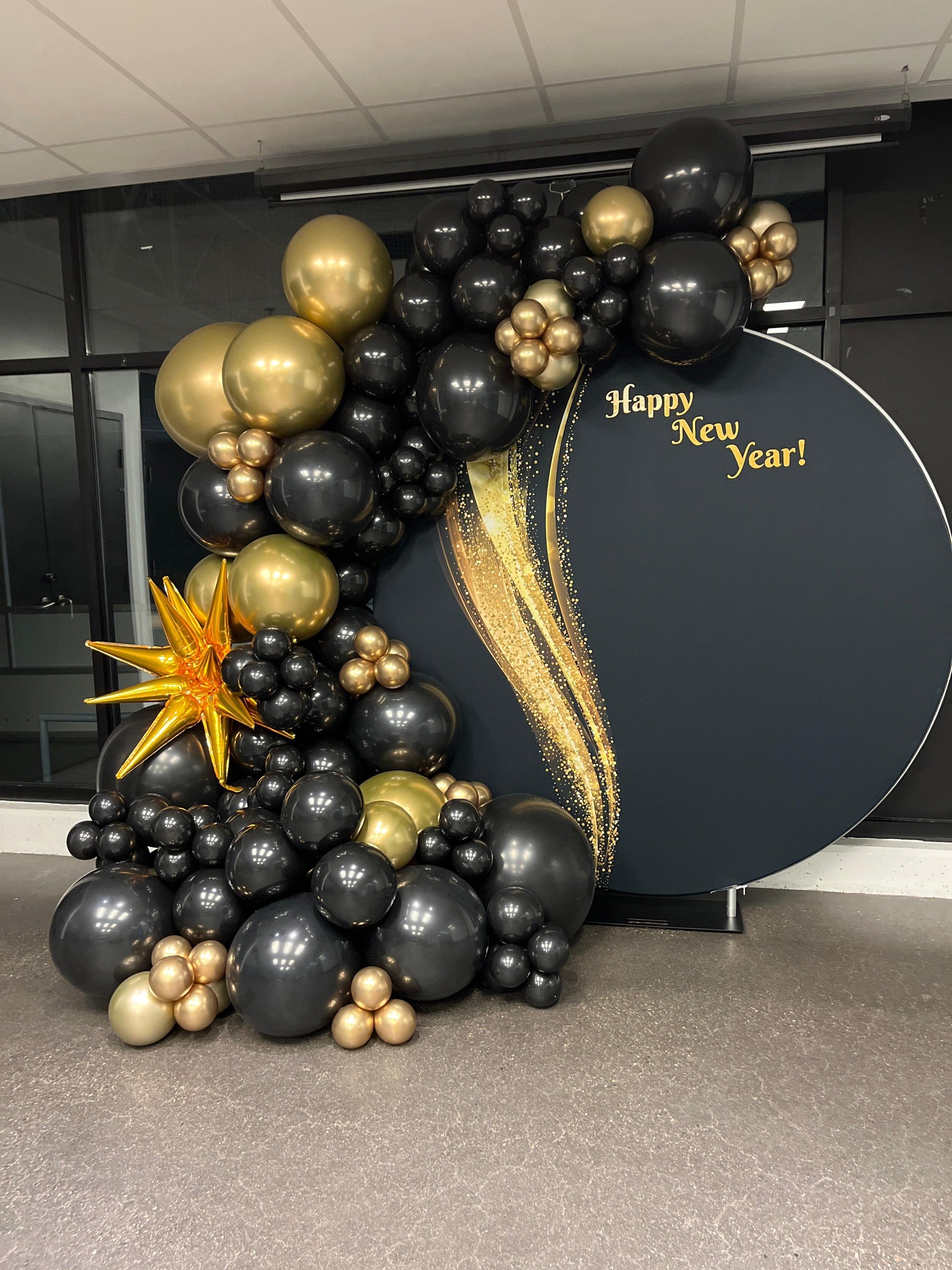 black and gold balloons around a large frame which says Happy New Year