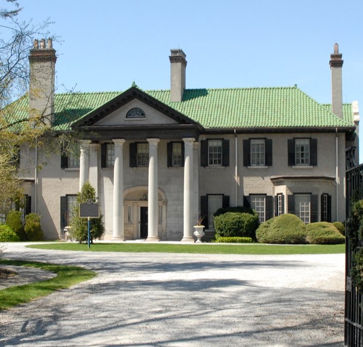 Front view of Parkwood Estate building, with greenery surrounding, and architecture of beige stone and green roof