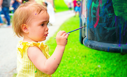 cute toddler painting on a vehicle