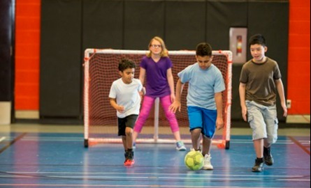 Kids playing soccer in a gym