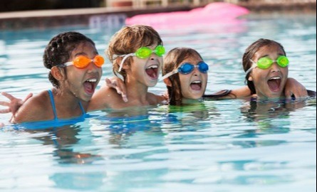 Four kids wearing goggles in a pool