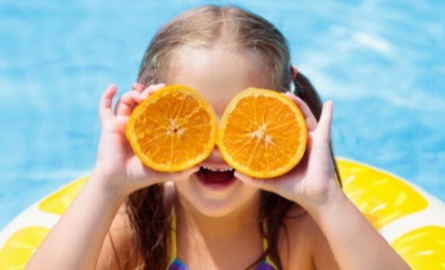A girl holding orange slices as eyes
