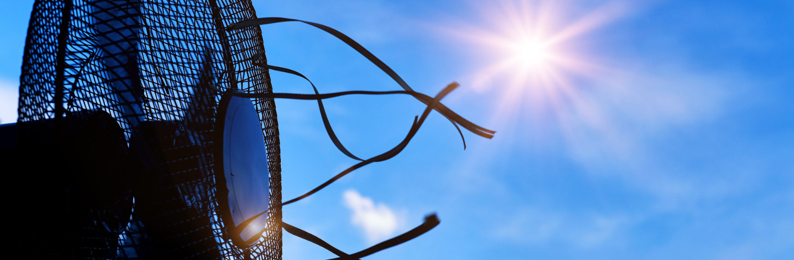 Black fan blowing wind in front of a blue sky