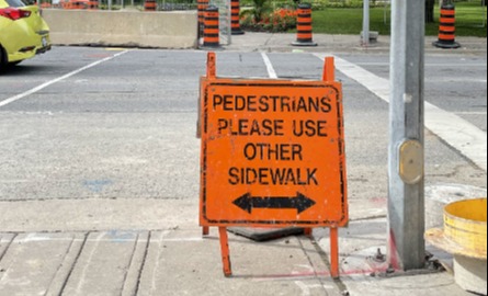 An orange sign telling pedestrians that the sidewalk is closed