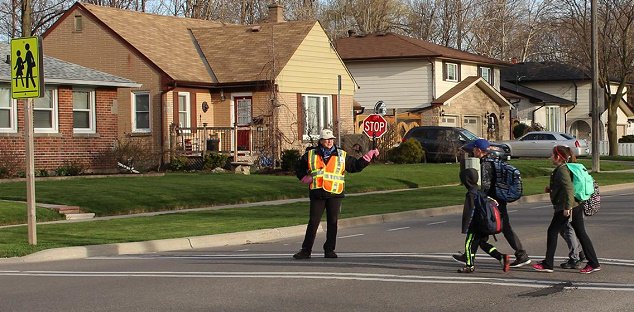 A crossing guard assisting patrons cross the road