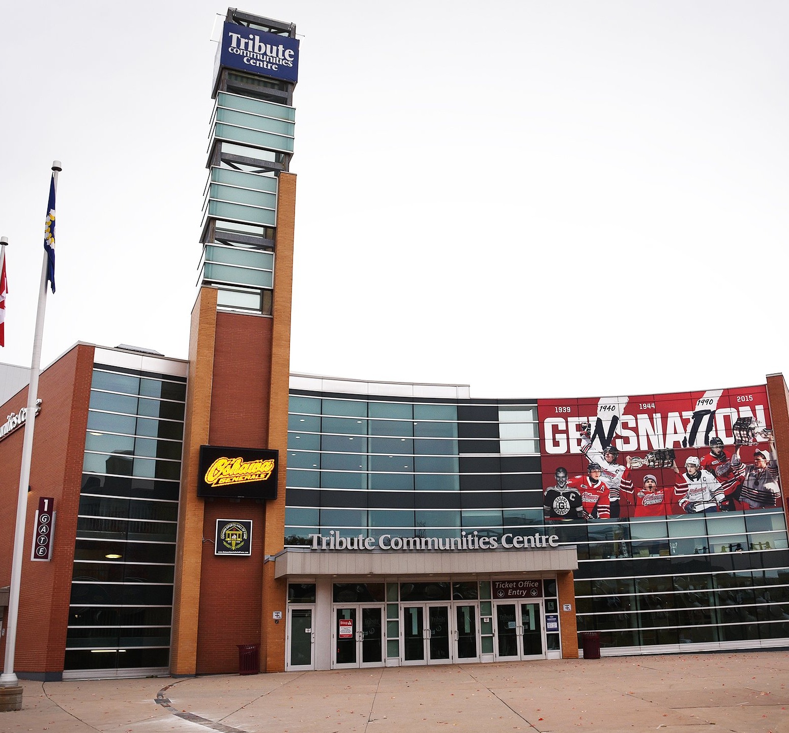 Street view of the building, with tall red brick walls, and glass windows below to a gift shop. Street lights are in view to the left and right of the frame.