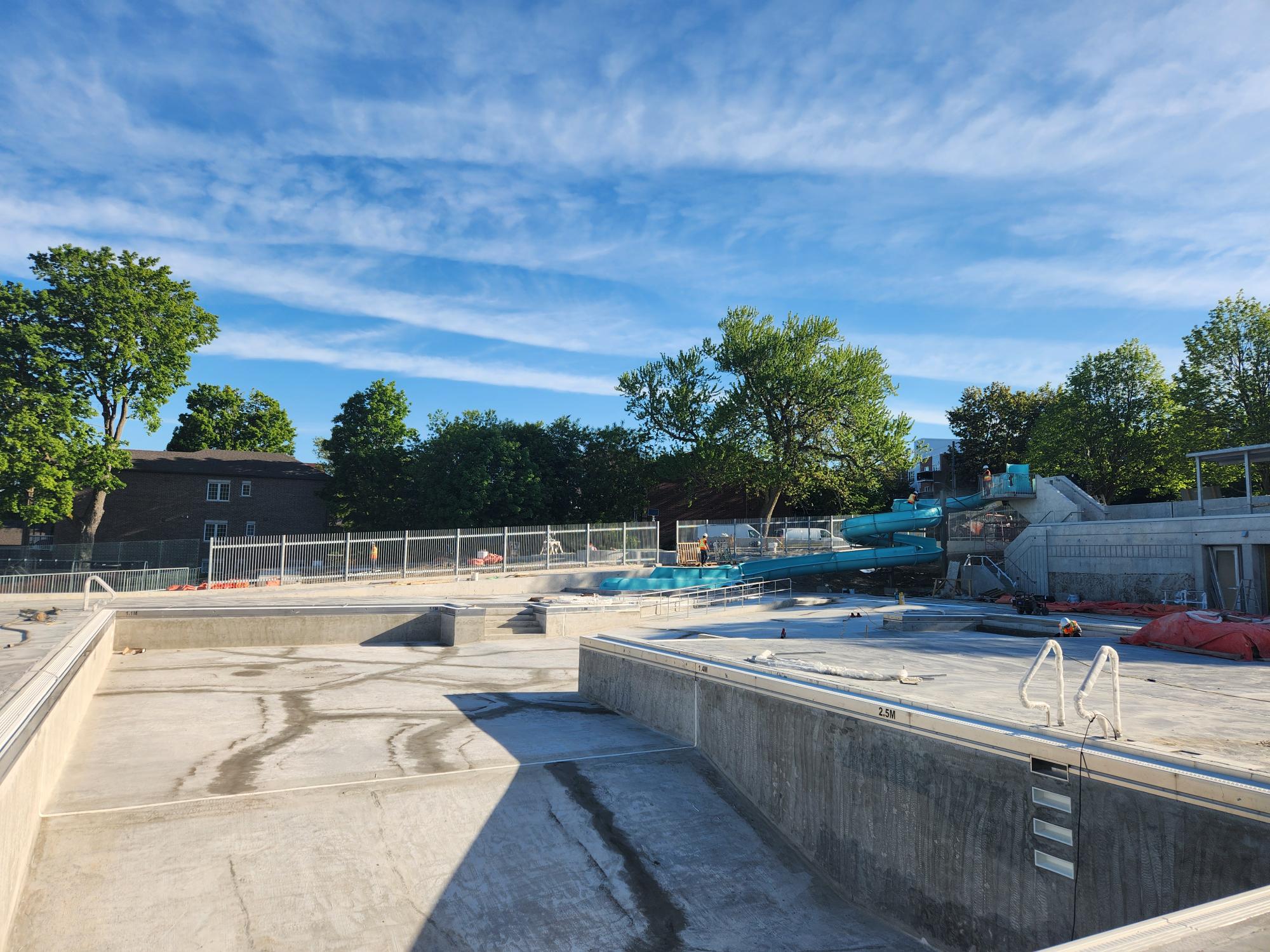 View of pool, pool deck and waterslide. Looking north towards Monck Street.