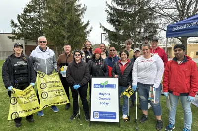 Mayor and group of volunteers standing with tent and sign
