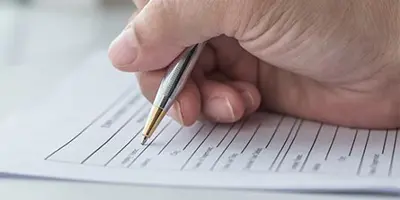 Hand holding a pen filling out a form.