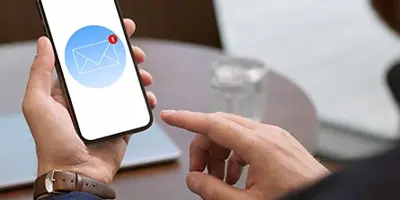 A hand over a mobile phone that is receiving a message