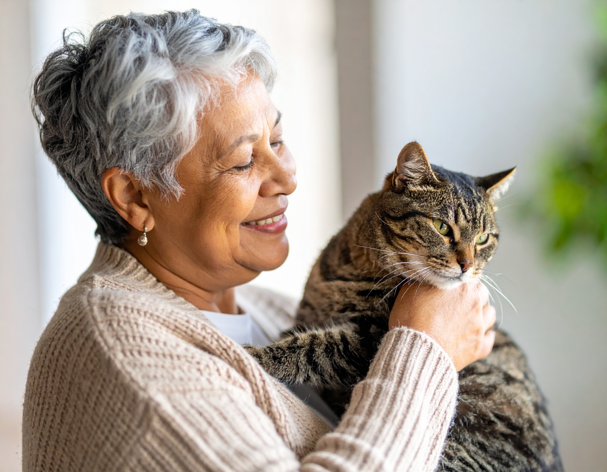 Senior holding a cat and smiling.