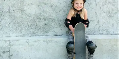 Young girl with skateboard leaning against wall