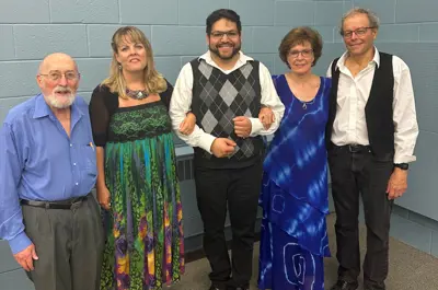 five performers posing and smiling for photo
