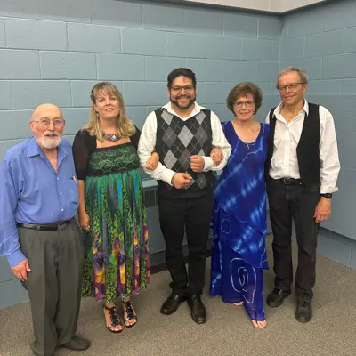 five performers posing and smiling for photo