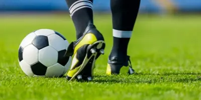 Person kicking soccer ball on field