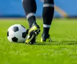 Person kicking soccer ball on field