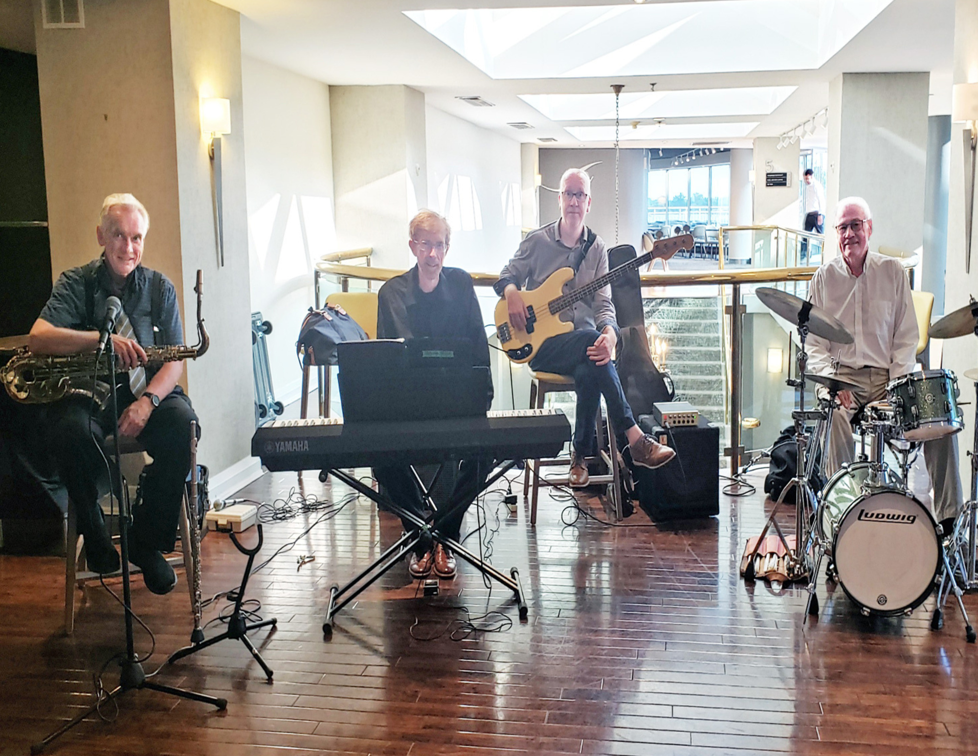 four musicians sitting with instruments in foyer